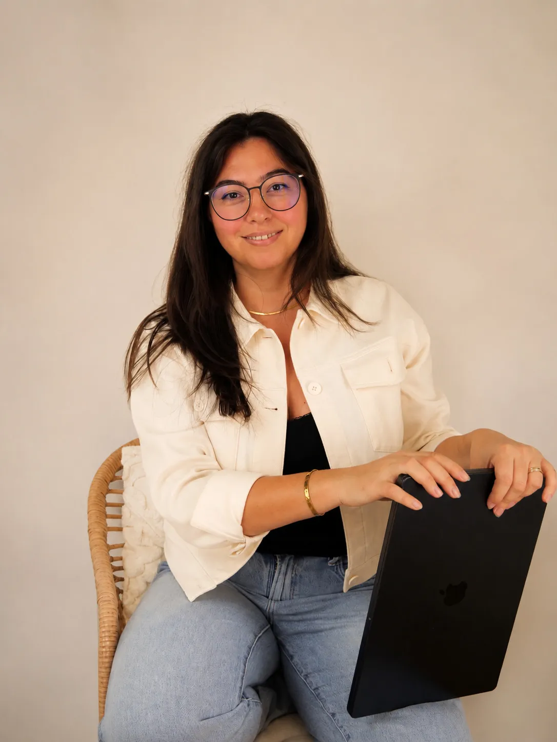 Ioana Orca, seated with a laptop against a warm neutral backdrop